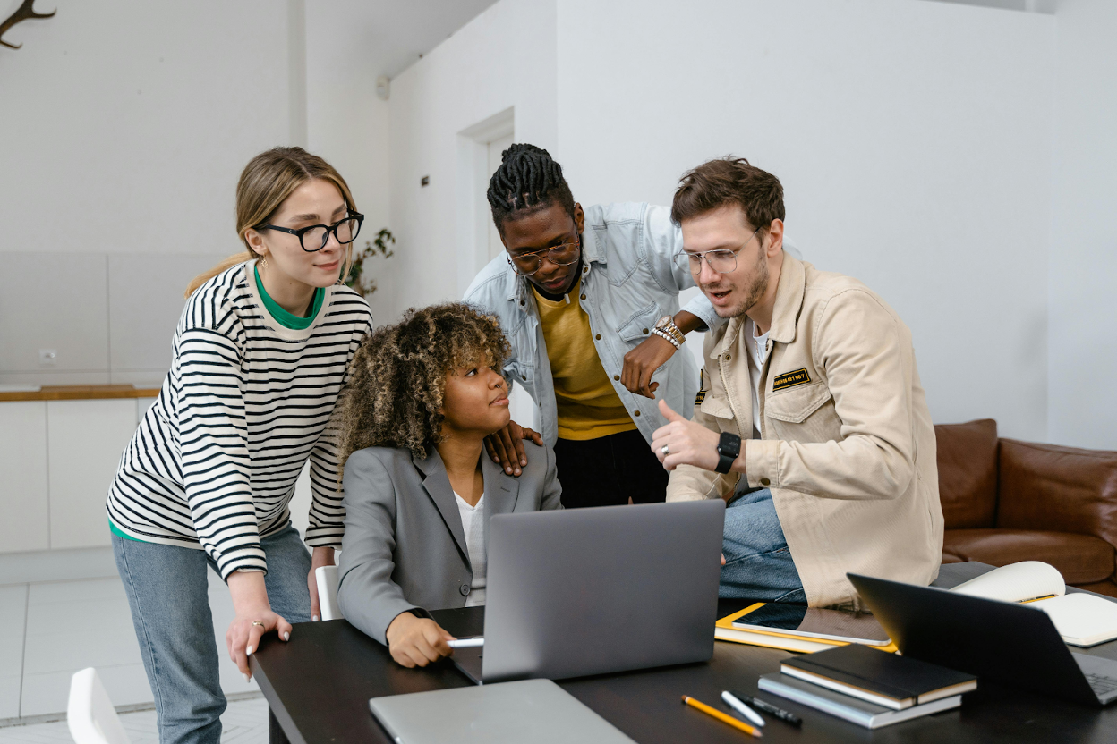 A team gathered around a laptop discussing viral trends and social media marketing strategies.