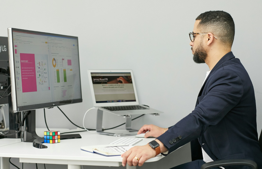 Professional comparing software dashboards on computer screens