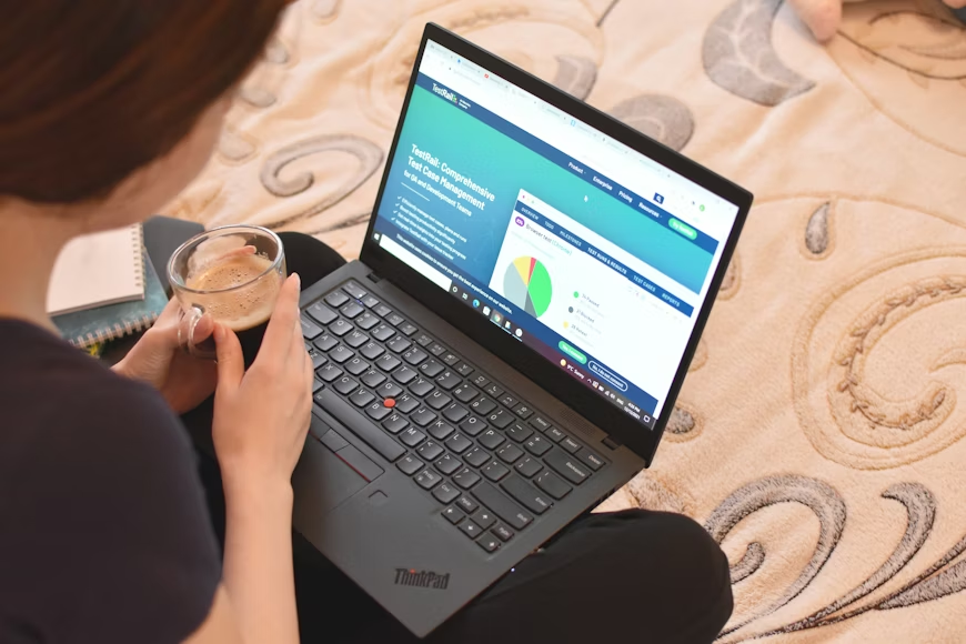 A person holding a cup with a laptop showing a pie chart.