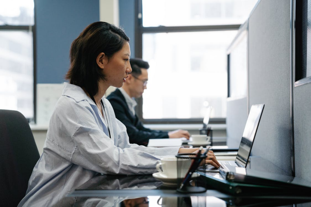 Two people working on laptops in an office setting.