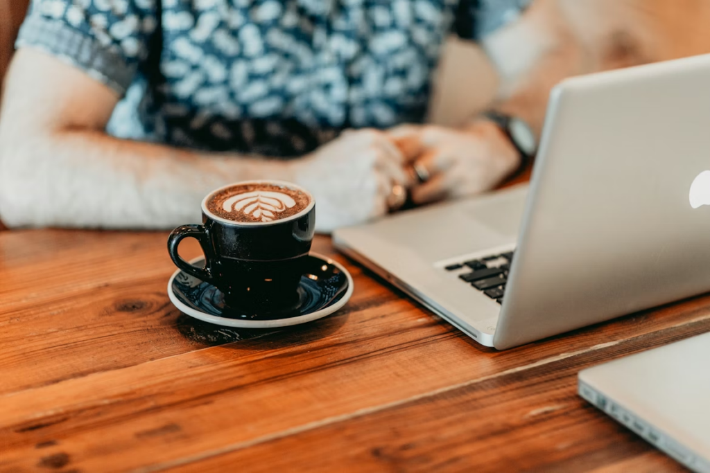 A person working on a financial advisor press release on a laptop at a wooden desk.