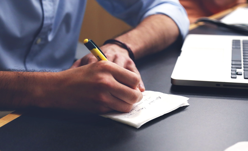 A person drafting press release headlines on a piece of paper.