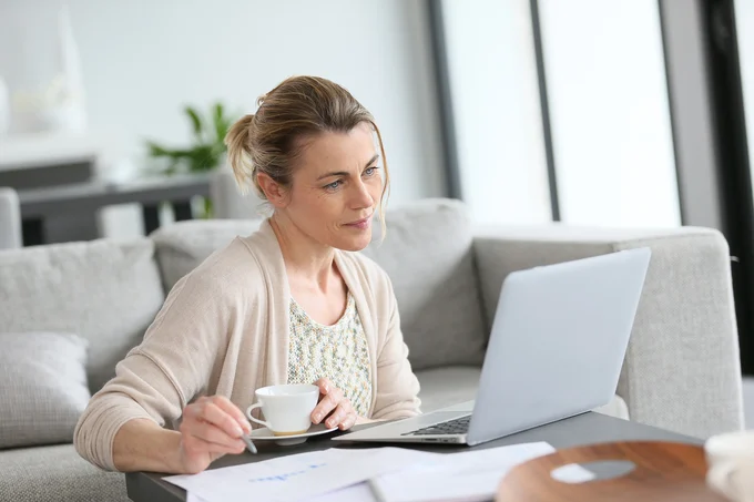 Woman reviewing documents on a laptop while managing a timely cyber attack press release response.