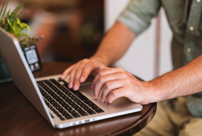 Writer drafting a skincare press release on a laptop with notes and product samples nearby.