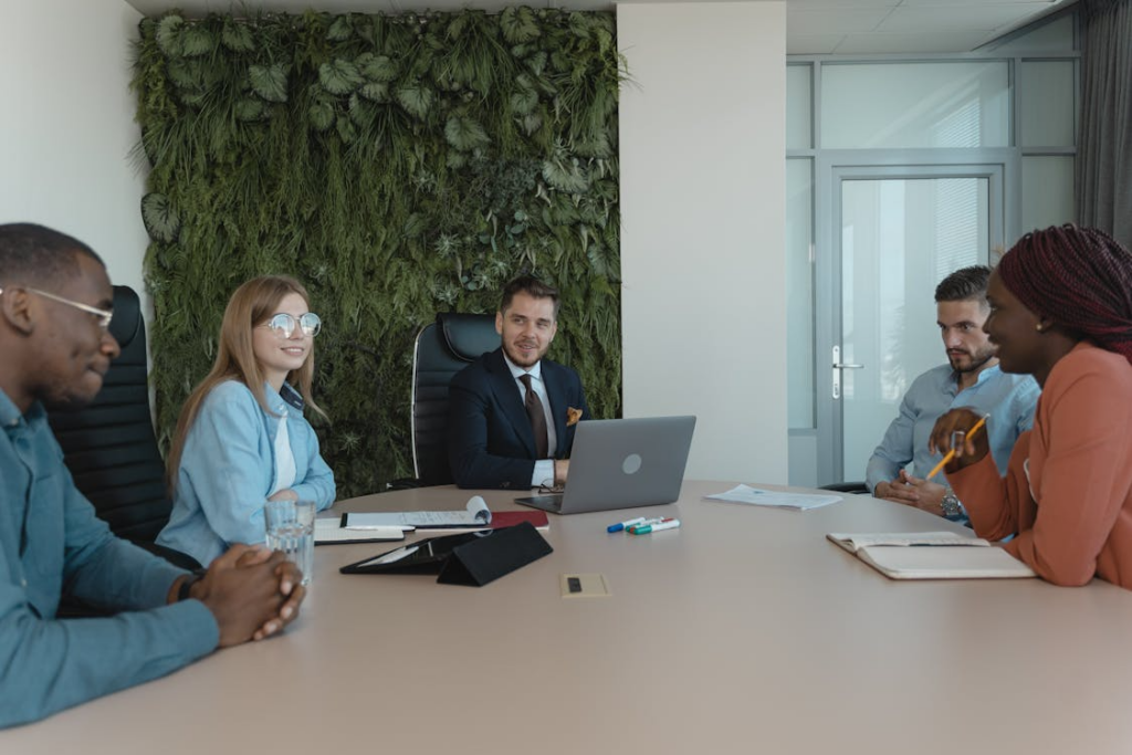 Team meeting in a room with a green plant wall, discussing ESG press release strategy and metrics.