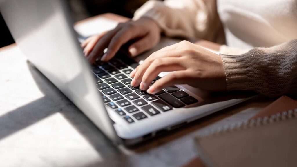 A person writing a press release headline on a computer.