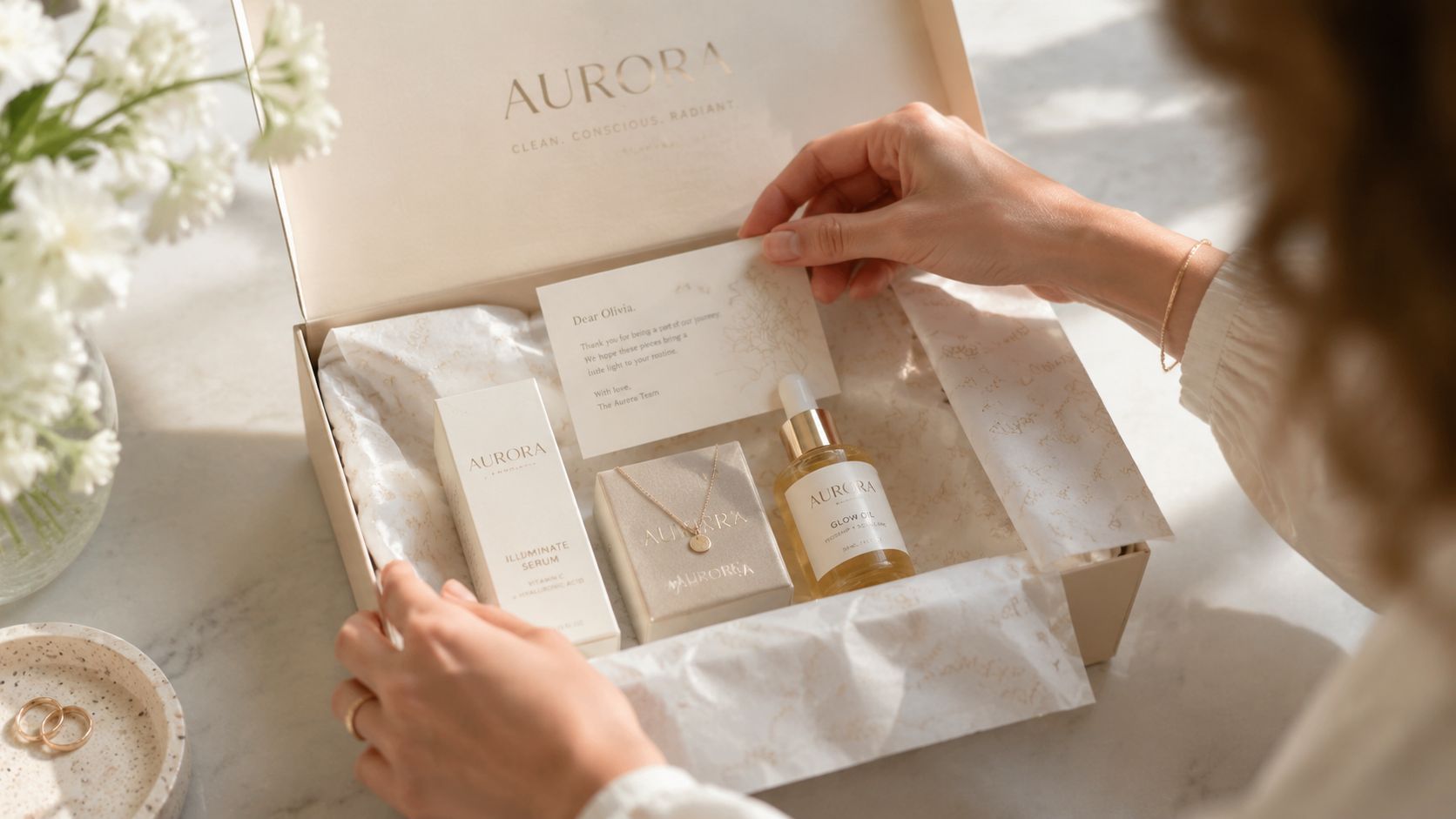 A person opening a luxury branded Aurora beauty and jewelry gift set on a marble surface.